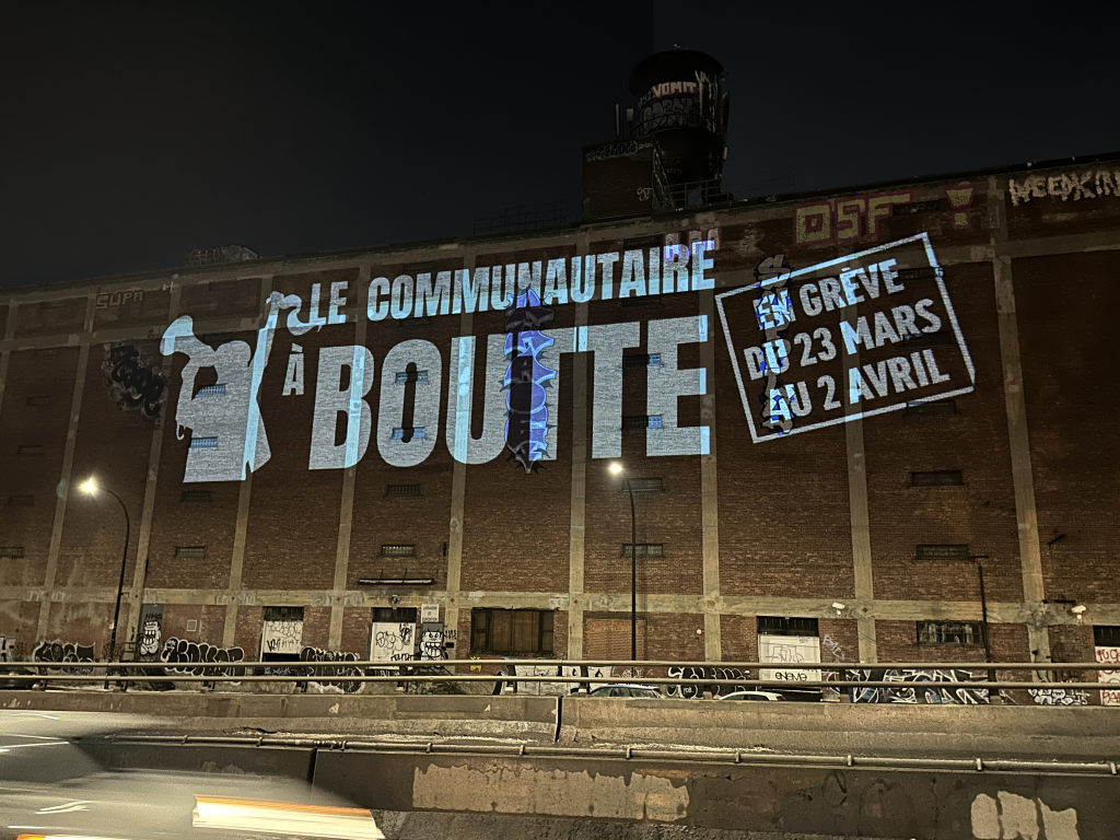 Image de la projection d'une bannière Le communautaire à boutte sur l'édifice Van Horne à Montréal